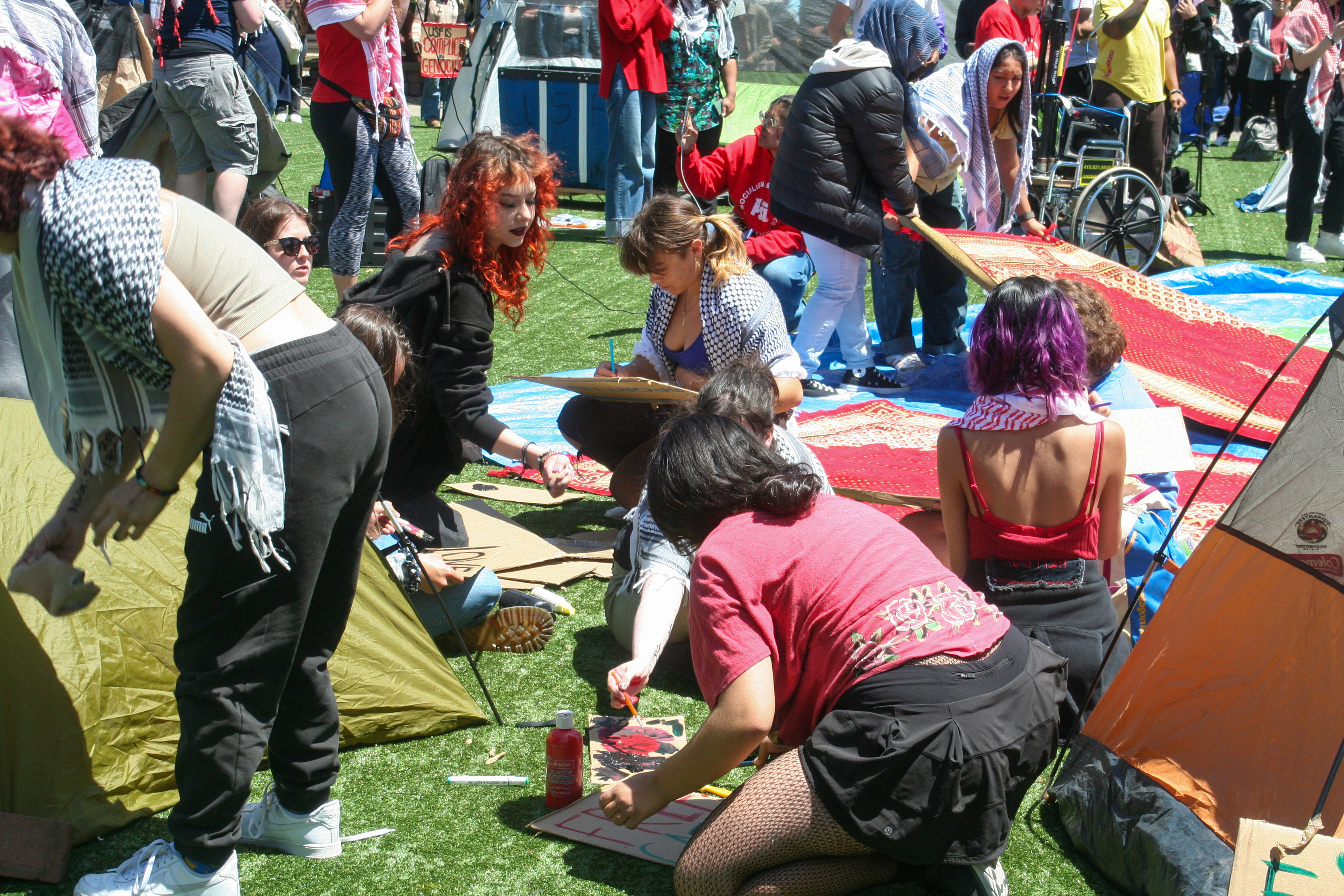 students decorate signs while others lay out rugs for prayer